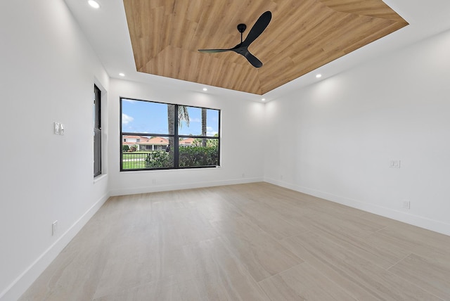 spare room with ceiling fan, a raised ceiling, and wooden ceiling