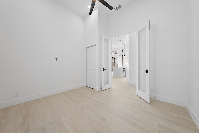 unfurnished room featuring french doors and a towering ceiling