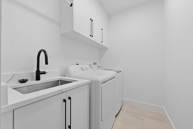 clothes washing area with cabinets, light tile patterned floors, washer and clothes dryer, and sink