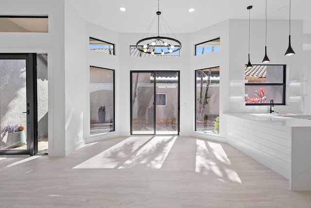 interior space with plenty of natural light, a chandelier, a high ceiling, and sink