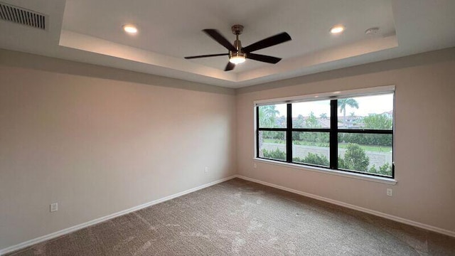 carpeted empty room featuring ceiling fan and a tray ceiling