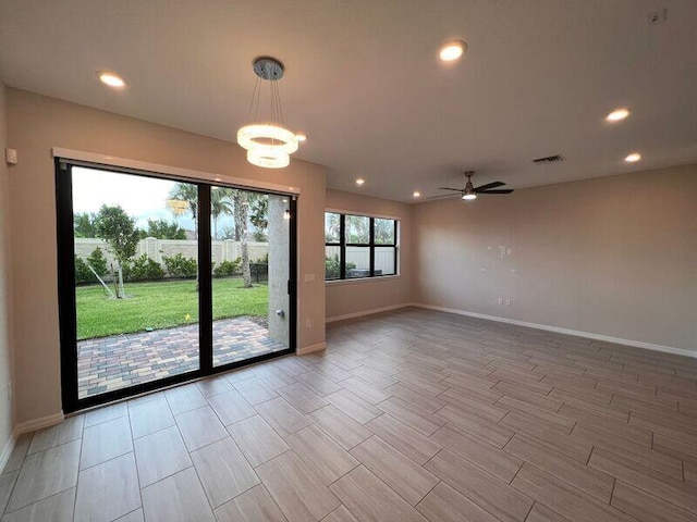 empty room featuring ceiling fan with notable chandelier