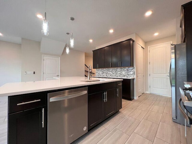 kitchen with tasteful backsplash, stainless steel appliances, sink, decorative light fixtures, and a center island with sink