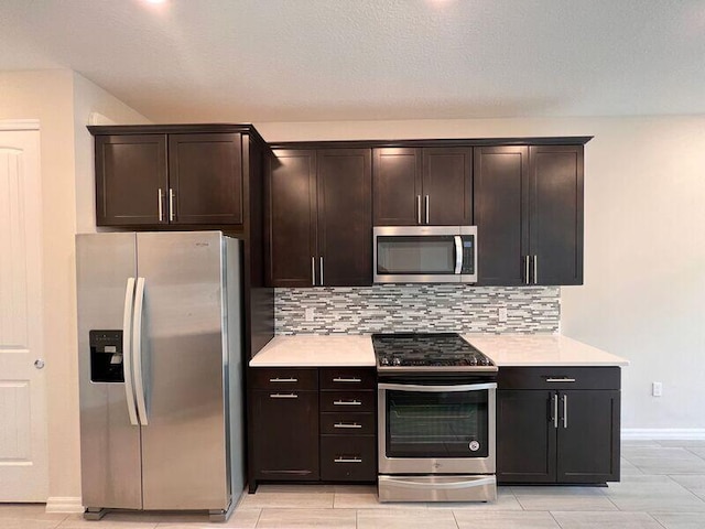 kitchen featuring a textured ceiling, decorative backsplash, dark brown cabinets, and stainless steel appliances