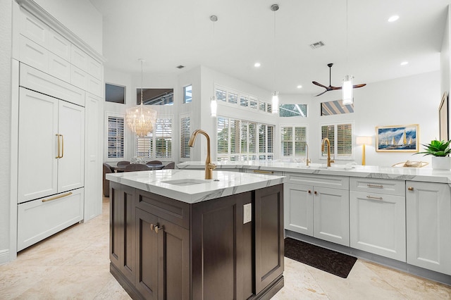 kitchen with light stone countertops, sink, paneled built in fridge, and decorative light fixtures