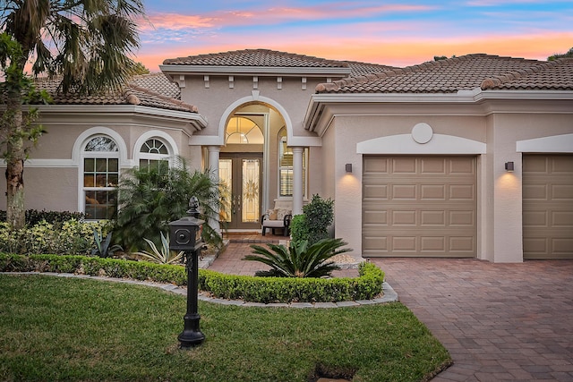 mediterranean / spanish house featuring a garage, a yard, and french doors