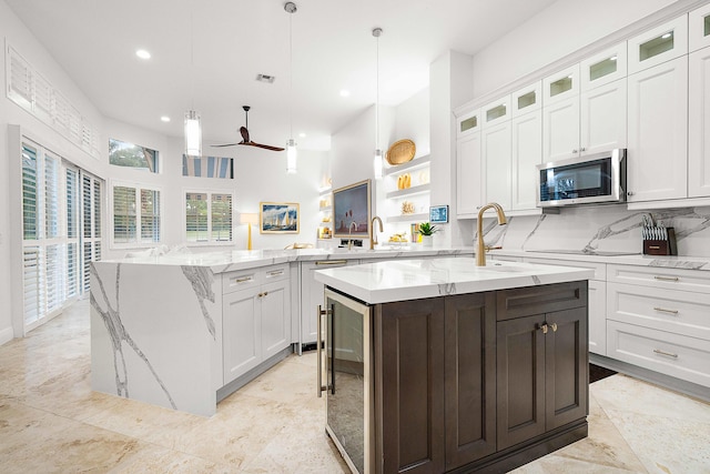 kitchen featuring pendant lighting, kitchen peninsula, a kitchen island with sink, and white cabinets