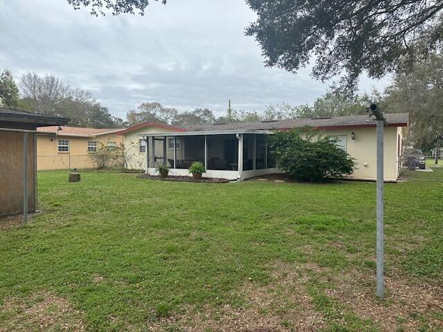 rear view of property featuring a sunroom and a yard