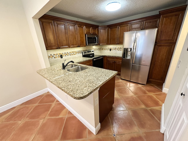 kitchen featuring sink, backsplash, kitchen peninsula, and appliances with stainless steel finishes