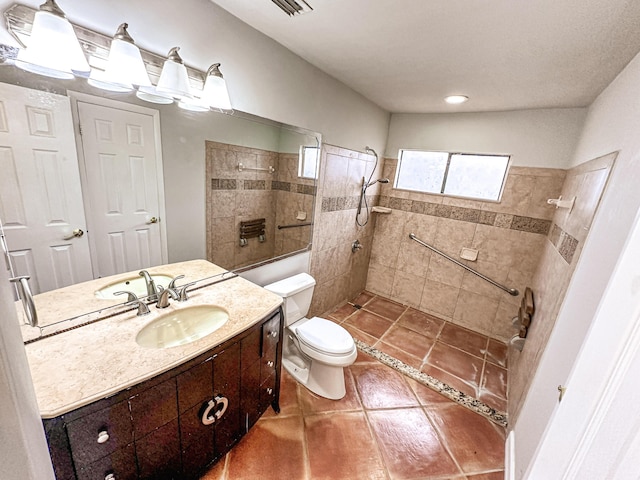 bathroom featuring toilet, tile patterned flooring, a tile shower, and vanity