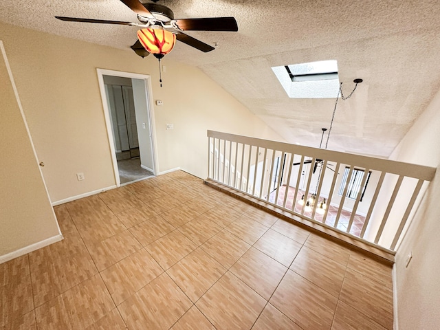 unfurnished room featuring a textured ceiling, ceiling fan, and vaulted ceiling with skylight