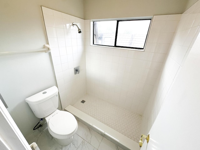 bathroom featuring a tile shower and toilet