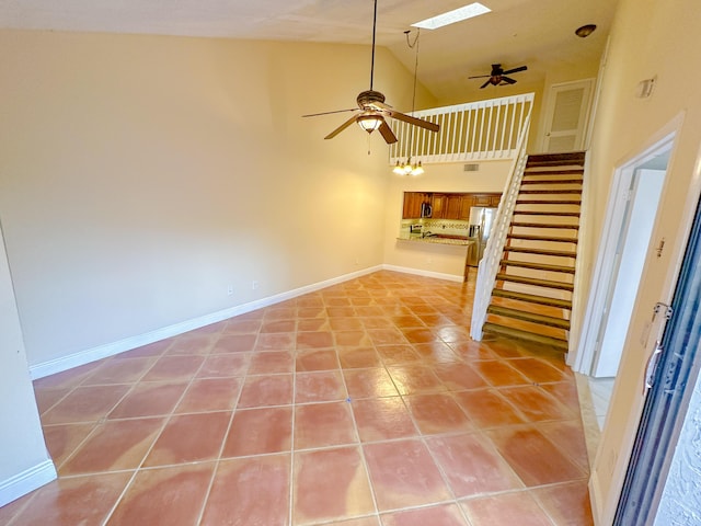 interior space with high vaulted ceiling, a skylight, light tile patterned floors, and ceiling fan