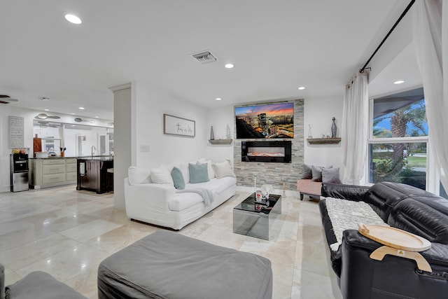 living room featuring ceiling fan and a stone fireplace