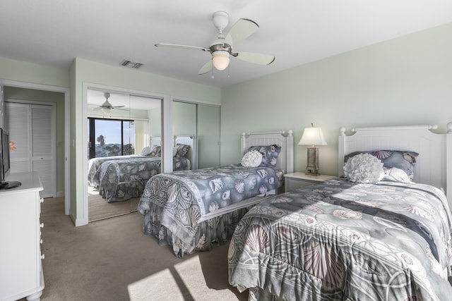 carpeted bedroom featuring ceiling fan and two closets