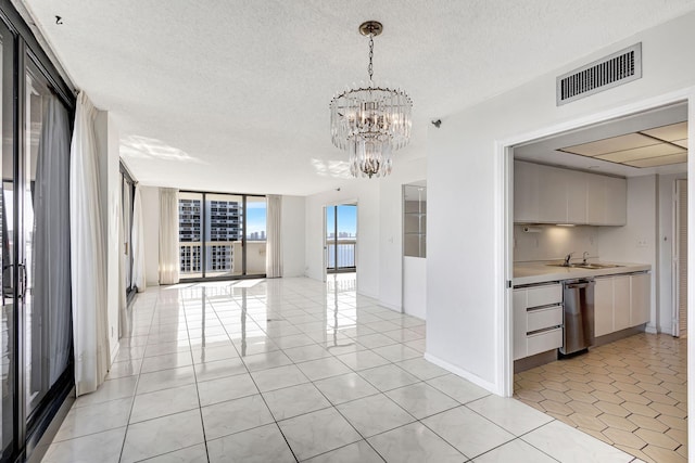 unfurnished dining area featuring a notable chandelier, light tile patterned flooring, sink, and a textured ceiling