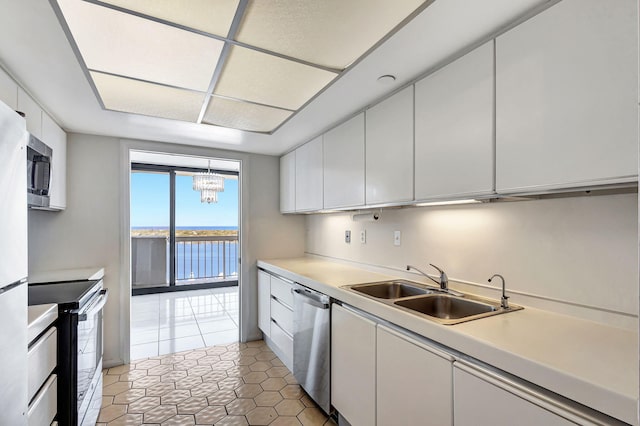 kitchen with white cabinetry, sink, stainless steel appliances, tile patterned floors, and a water view