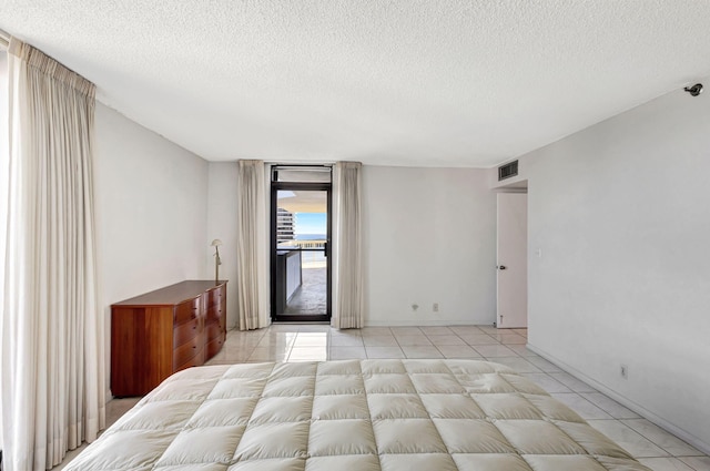 unfurnished bedroom with access to exterior, light tile patterned flooring, and a textured ceiling