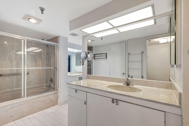 bathroom featuring tile patterned flooring, vanity, and bath / shower combo with glass door