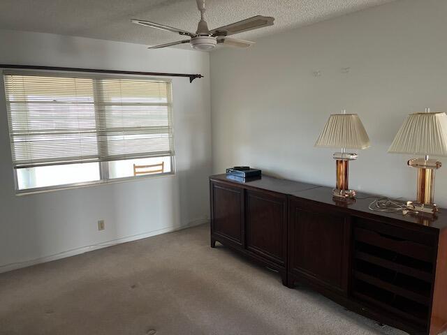 carpeted bedroom featuring a textured ceiling, multiple windows, and ceiling fan