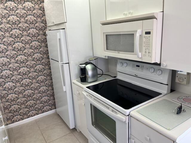 kitchen featuring light tile patterned floors, white cabinets, and white appliances