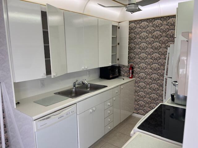 kitchen featuring white cabinetry, dishwasher, sink, light tile patterned flooring, and range