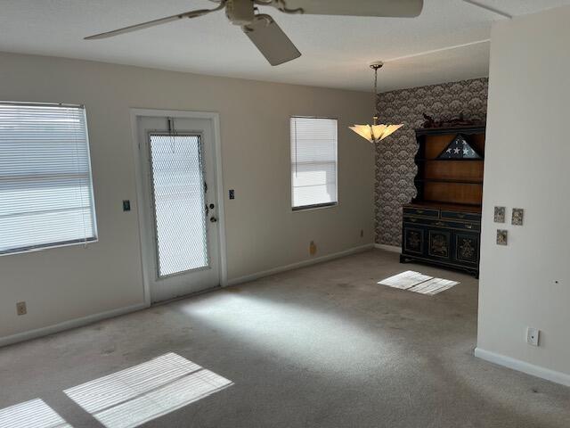 carpeted spare room featuring ceiling fan with notable chandelier