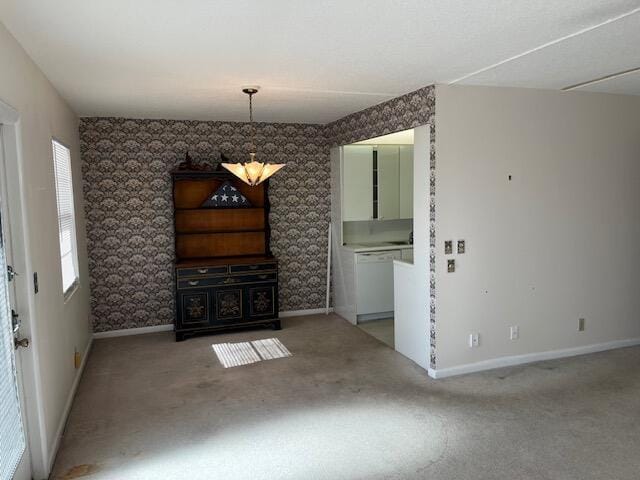 unfurnished dining area featuring carpet flooring and an inviting chandelier