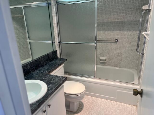 full bathroom featuring tile patterned flooring, vanity, toilet, and combined bath / shower with glass door