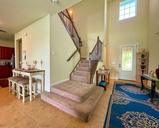 entryway with light tile patterned floors and a high ceiling