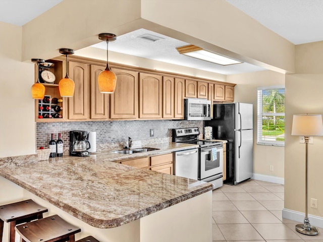 kitchen featuring stainless steel appliances, backsplash, a sink, and a peninsula