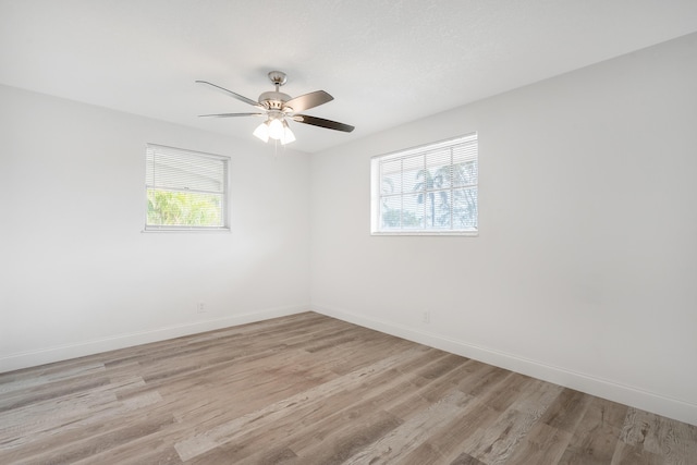 empty room with ceiling fan, plenty of natural light, and light wood-type flooring