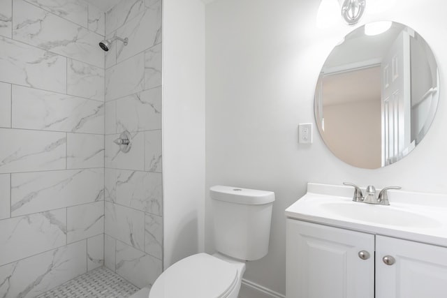 bathroom featuring a tile shower, vanity, and toilet