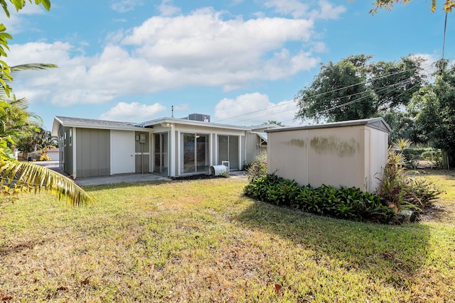 rear view of property with a sunroom, cooling unit, and a lawn