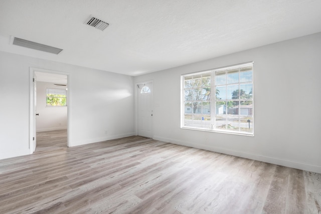 spare room featuring light hardwood / wood-style floors and a textured ceiling