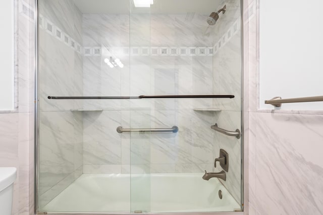 bathroom with shower / bath combination with glass door and toilet