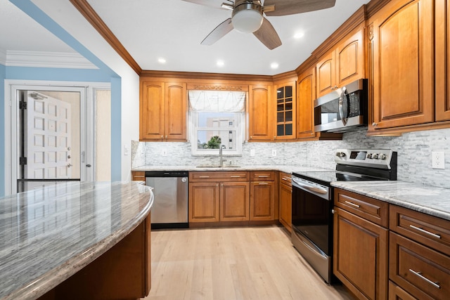 kitchen featuring sink, decorative backsplash, ornamental molding, appliances with stainless steel finishes, and light stone counters