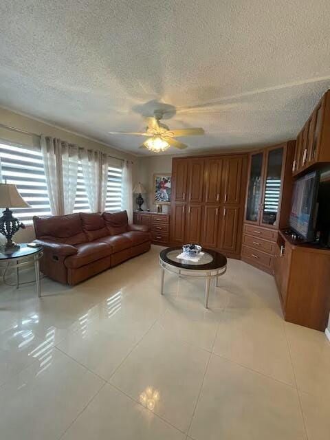 living room featuring a textured ceiling, ceiling fan, and light tile patterned flooring