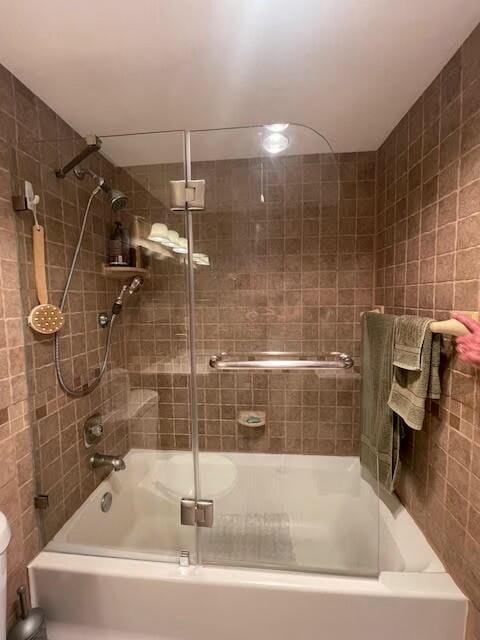 bathroom with shower / bath combination with glass door and tile walls