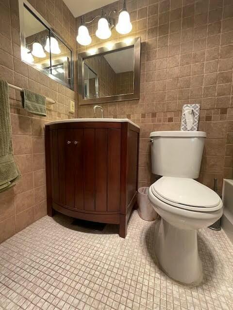 bathroom with tile patterned flooring, vanity, toilet, and tile walls