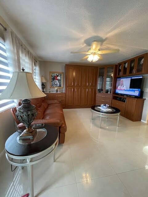 tiled living room with a textured ceiling and ceiling fan