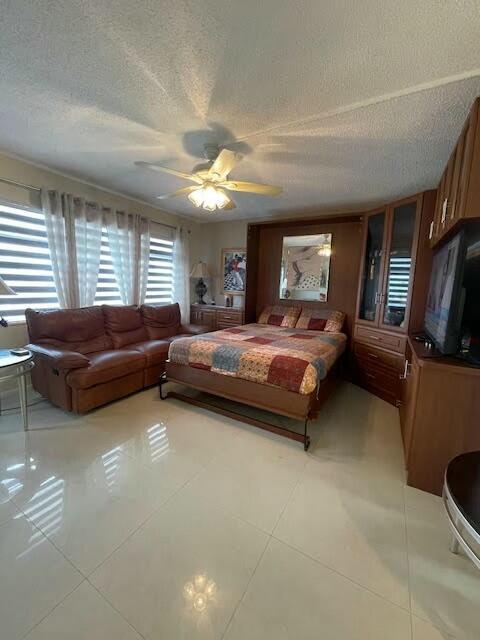 tiled bedroom featuring ceiling fan and a textured ceiling