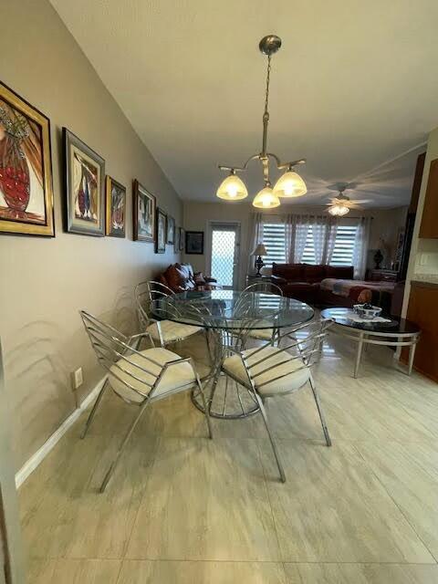 dining room with hardwood / wood-style floors, a healthy amount of sunlight, and ceiling fan with notable chandelier