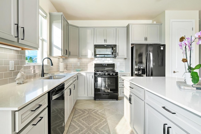 kitchen featuring black appliances, light tile patterned floors, sink, and tasteful backsplash