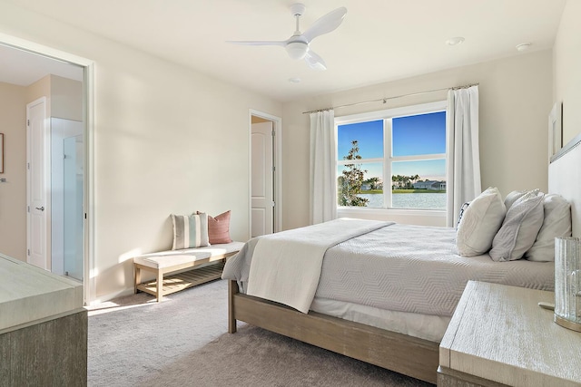 carpeted bedroom featuring ceiling fan and a water view