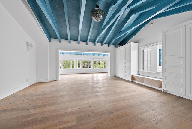 unfurnished living room with vaulted ceiling with beams and light wood-type flooring