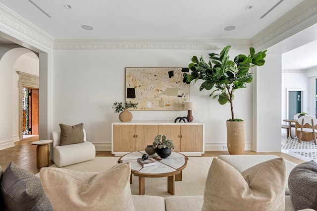 living area with light wood finished floors, baseboards, arched walkways, and crown molding