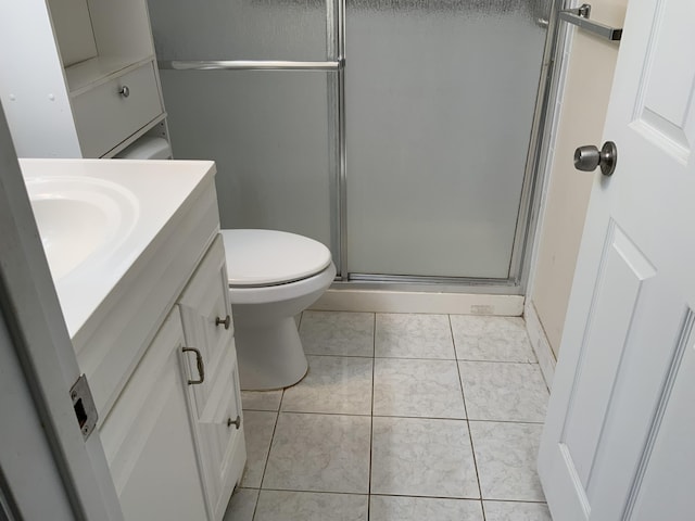 bathroom featuring tile patterned flooring, vanity, toilet, and a shower with door