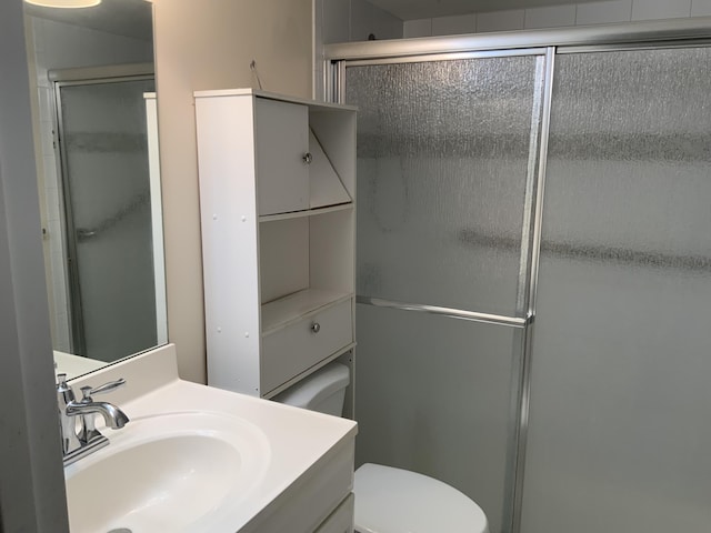 bathroom featuring vanity, toilet, and a shower with shower door