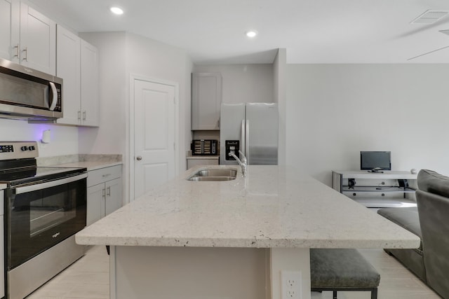 kitchen featuring white cabinetry, sink, appliances with stainless steel finishes, and an island with sink